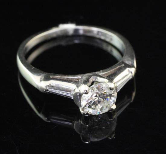 An 18ct white gold and single stone diamond ring with trapeze cut diamond set shoulders, size L.